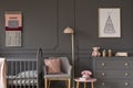 Grey armchair with pink pillow between bed and cabinet in child`