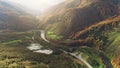 Grey asphalt road at blue winding mountain river lit by sun Royalty Free Stock Photo