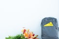 Grey backpack with a yellow notebook and flowers on a soft blue background. Banner design. Back to school. First september.