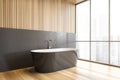 Grey bathtub on wooden floor in bathroom near window, wooden design Royalty Free Stock Photo