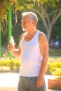 Grey Bearded Old Man in Vest Holds Water Bottle in Park Royalty Free Stock Photo