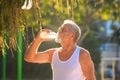 Grey Bearded Old Man in Vest Holds Water Bottle in Park Royalty Free Stock Photo