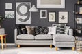 Grey and black pillows on comfortable corner sofa in scandinavian living room