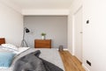 Grey blanket on bed in minimal bedroom interior with plant on ca