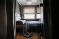 Grey blanket and pillows on bed in simple hotel bedroom interior