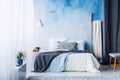 Grey and blue bedding on bed in spacious bedroom interior with l Royalty Free Stock Photo