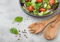 Grey bowl with healthy fresh vegetables salad with lettuce and tomatoes, red onion and spinach on light background with spatula Royalty Free Stock Photo