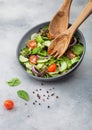 Grey bowl in motion with healthy fresh vegetables salad with lettuce and tomatoes, red onion and spinach on light background with Royalty Free Stock Photo