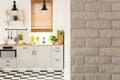 Grey brick wall in bright kitchen interior with lamps above coun