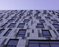 Grey building with Windows, view from below, blue sky. Graphically