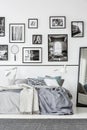 Carpet in front of bed and mirror in white and black bedroom interior with gallery. Real photo