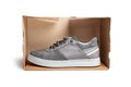 Grey casual sports shoes/sneaker in a brown cardboard box isolated on a white background Royalty Free Stock Photo