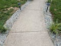 Grey cement path with solar lights and grasses