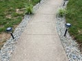 Grey cement path with solar lights and grasses