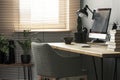 Grey chair at wooden desk with books and desktop computer in bri Royalty Free Stock Photo