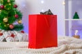 A grey chartreux cat look out of a red gift wrapping bag. A cat on the background of Christmas tree, garlands, gifts Royalty Free Stock Photo