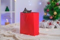 A grey chartreux cat look out of a red gift wrapping bag. A cat on the background of Christmas tree, garlands, gifts Royalty Free Stock Photo