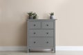 Grey chest of drawers with houseplants near beige wall