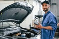 Grey colored oil can in hands. Auto mechanic working in garage. Repair service Royalty Free Stock Photo