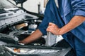 Grey colored oil can in hands. Auto mechanic working in garage. Repair service Royalty Free Stock Photo