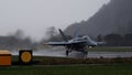 Grey combat aircraft takes off in a raining day