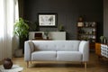 Grey couch in vintage living room interior with wooden cupboard, poster and plant. Real photo Royalty Free Stock Photo