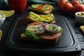 Grey cutting board with sandwich with tomato, egg and purple onion and avocado and cheese sandwich Royalty Free Stock Photo