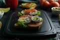 Grey cutting board with sandwiches with ham, lettuce and tomatoes and sandwich with tomatoes, egg and purple onion Royalty Free Stock Photo