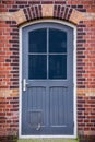 Grey door with windows in a stone brick wall with a cat  flap Royalty Free Stock Photo