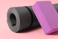 Grey exercise mat and yoga block on pink background, closeup