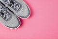 Grey female sneakers on pink background.