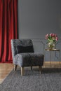 Grey floral chair with black cushion standing on dark carpet in elegant room interior with fresh tulips on gold metal table and re Royalty Free Stock Photo