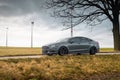 grey Ford Mondeo on a narrow road in a field with wind turbines Royalty Free Stock Photo
