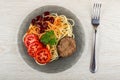 Plate with spaghetti, cutlet, red beans, tomato, parsley, fork on wooden table. Top view Royalty Free Stock Photo