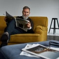 Grey hair caucasian man reading newspaper on sofa