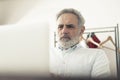 Grey-haired bearded male entrepreneur working on laptop focused middle-aged man Royalty Free Stock Photo