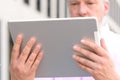 Grey-haired bearded man reading on a tablet Royalty Free Stock Photo