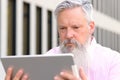 Grey-haired bearded man reading on a tablet Royalty Free Stock Photo