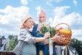 Grey-haired caring husband feeling nice after presenting field flowers his wife