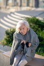 Grey-haired homeless woman feeling cold and miserable