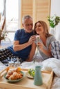 Grey-haired husband giving his appealing wife little pink flower Royalty Free Stock Photo