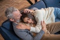 Grey-haired man sitting on the sofa and hugging his wife with tendernes Royalty Free Stock Photo