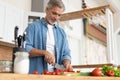 Grey-haired Mature handsome man preparing delicious and healthy food in the home kitchen. Royalty Free Stock Photo