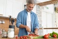 Grey-haired Mature handsome man preparing delicious and healthy food in the home kitchen. Royalty Free Stock Photo