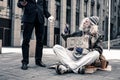 Grey-haired senior homeless carrying nameplate and taking bite food