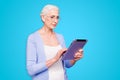 Grey haired old serious business woman wearing glasses, reading browsing using tablet, typing letter. Isolated over Royalty Free Stock Photo