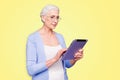 Grey haired old serious business woman wearing glasses, reading browsing using tablet, typing letter. Isolated over Royalty Free Stock Photo