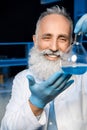 Grey haired scientist in lab coat holding flask with reagent at laboratory Royalty Free Stock Photo