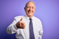 Grey haired senior business elegant man standing over purple isolated background doing happy thumbs up gesture with hand Royalty Free Stock Photo