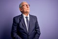 Grey haired senior business man wearing glasses and elegant suit and tie over purple background smiling looking to the side and Royalty Free Stock Photo